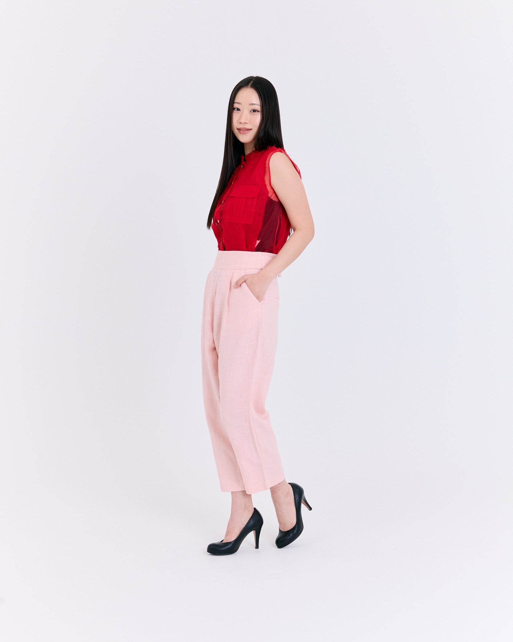 Woman wearing a red top and pink pants on a white background