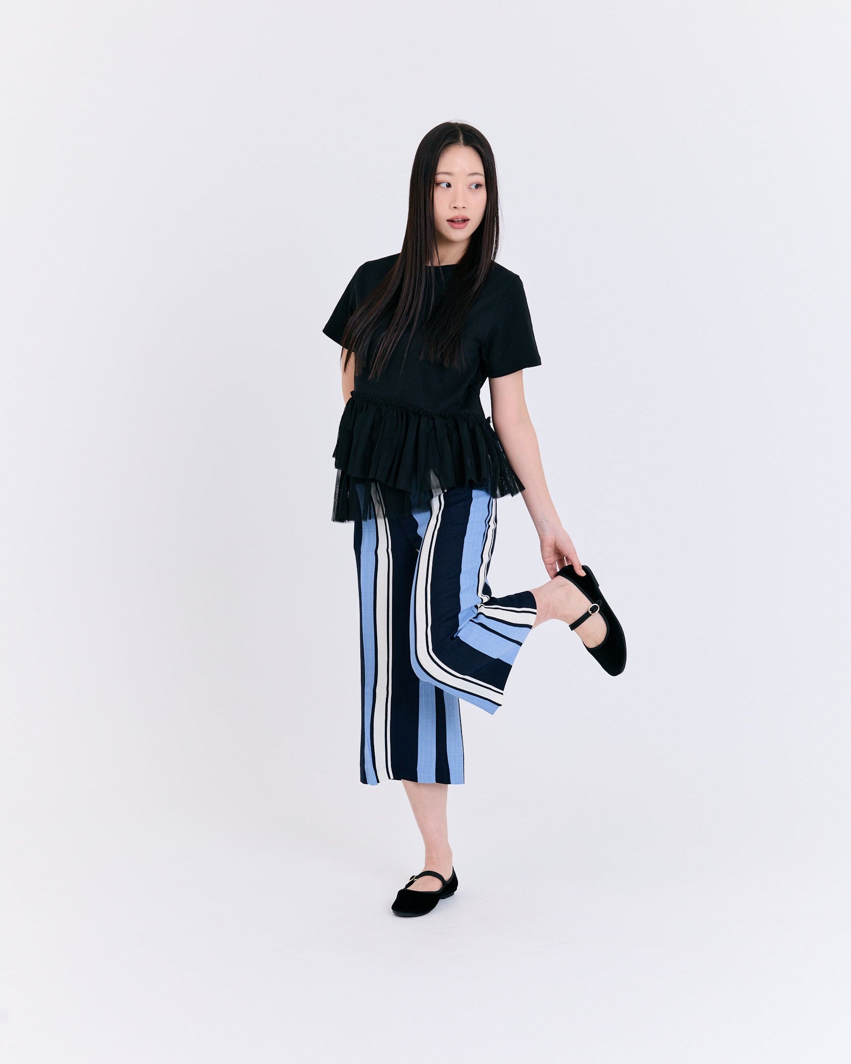 Woman wearing a black top and striped pants on a white background