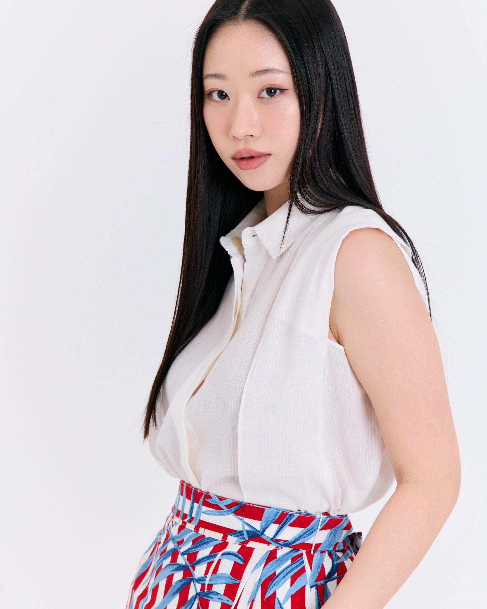 Woman wearing a white blouse and colorful skirt against a white background