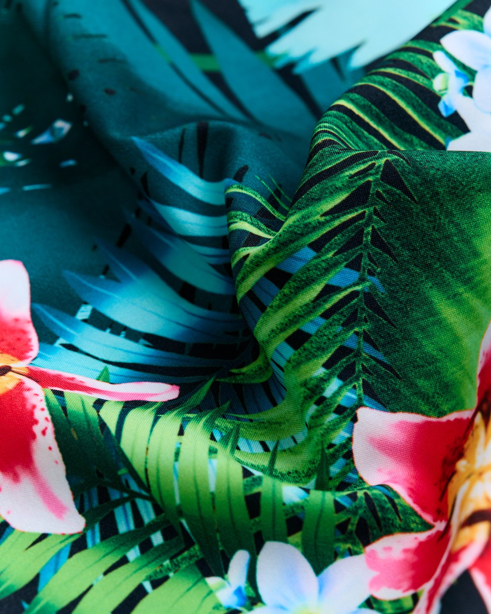 Close-up of a tropical-themed fabric with green leaves and colorful flowers.