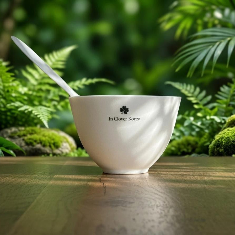 White bowl with a spoon on a wooden surface with greenery in the background