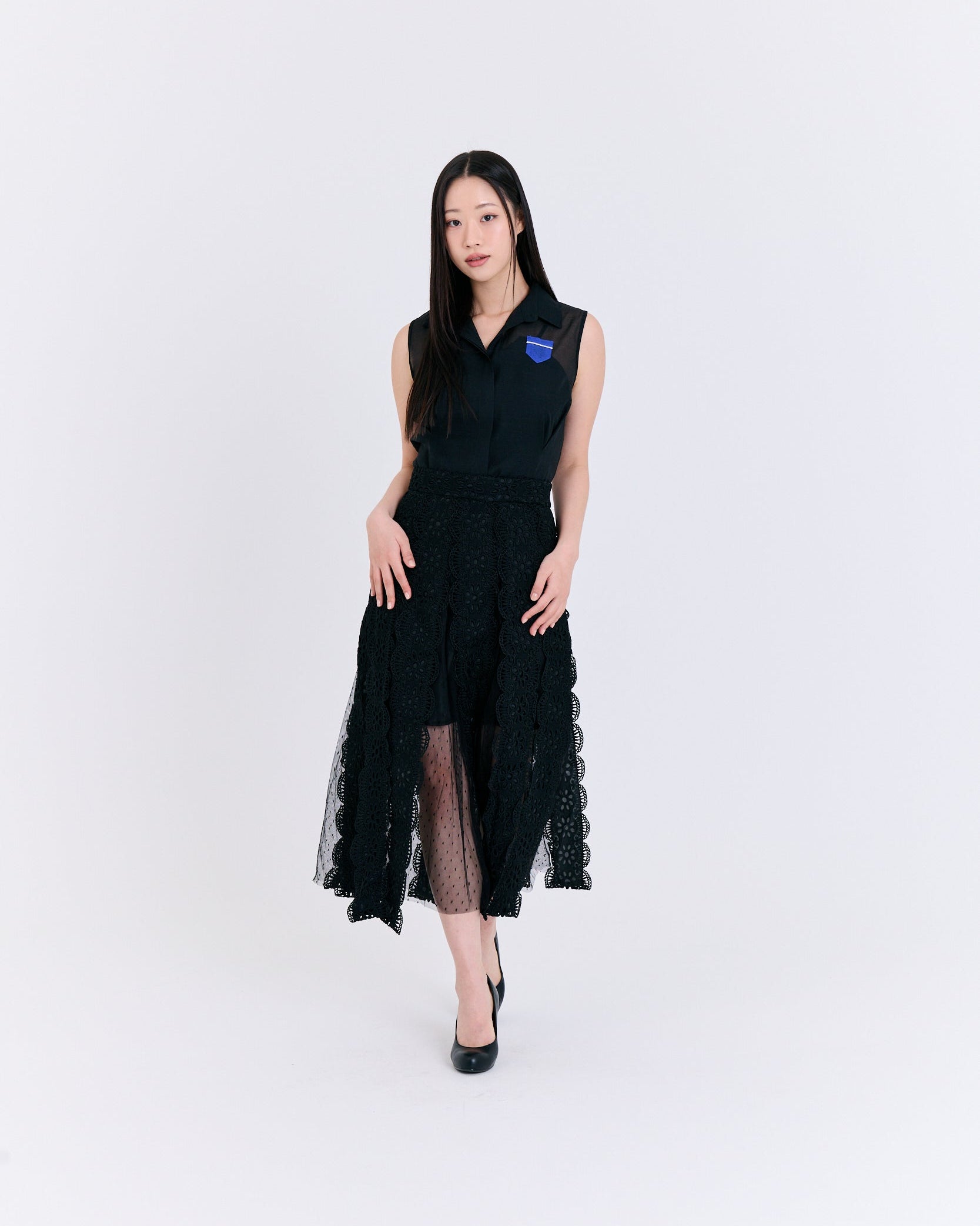 Woman wearing a black dress with sheer panels on a white background