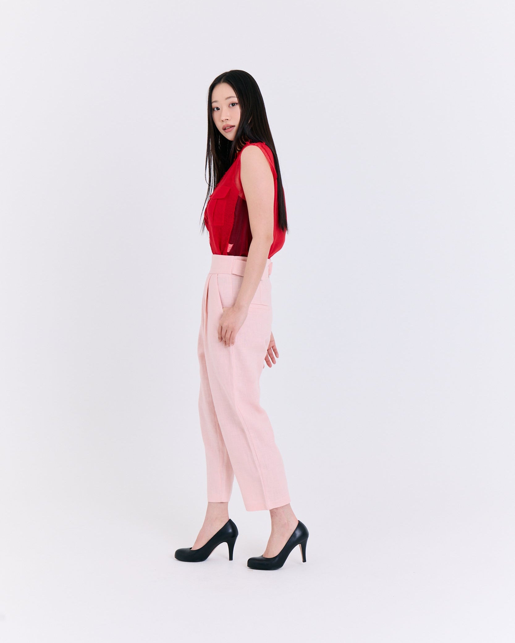 Woman wearing a red top and pink pants on a white background