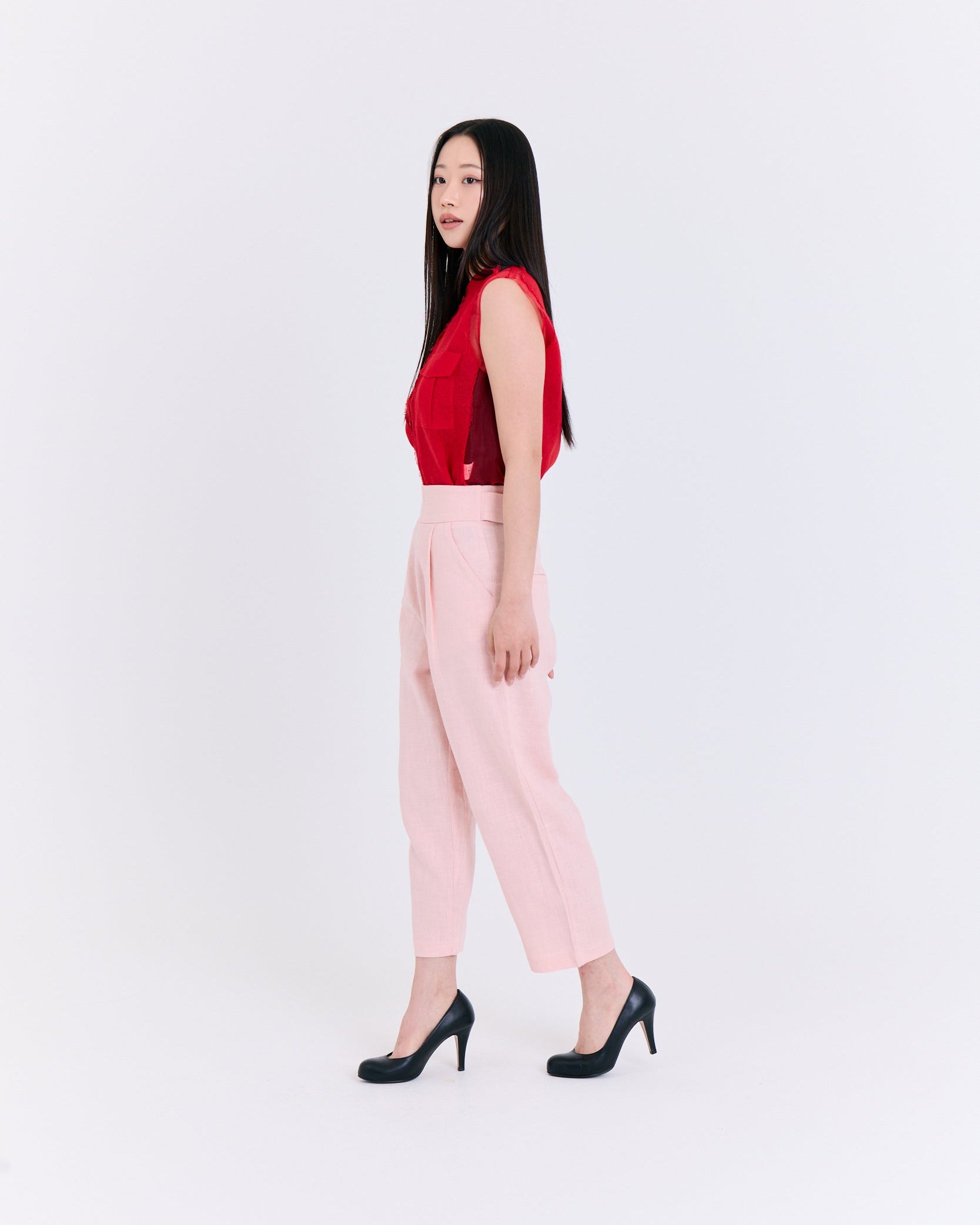 Woman wearing a red top and pink pants on a white background