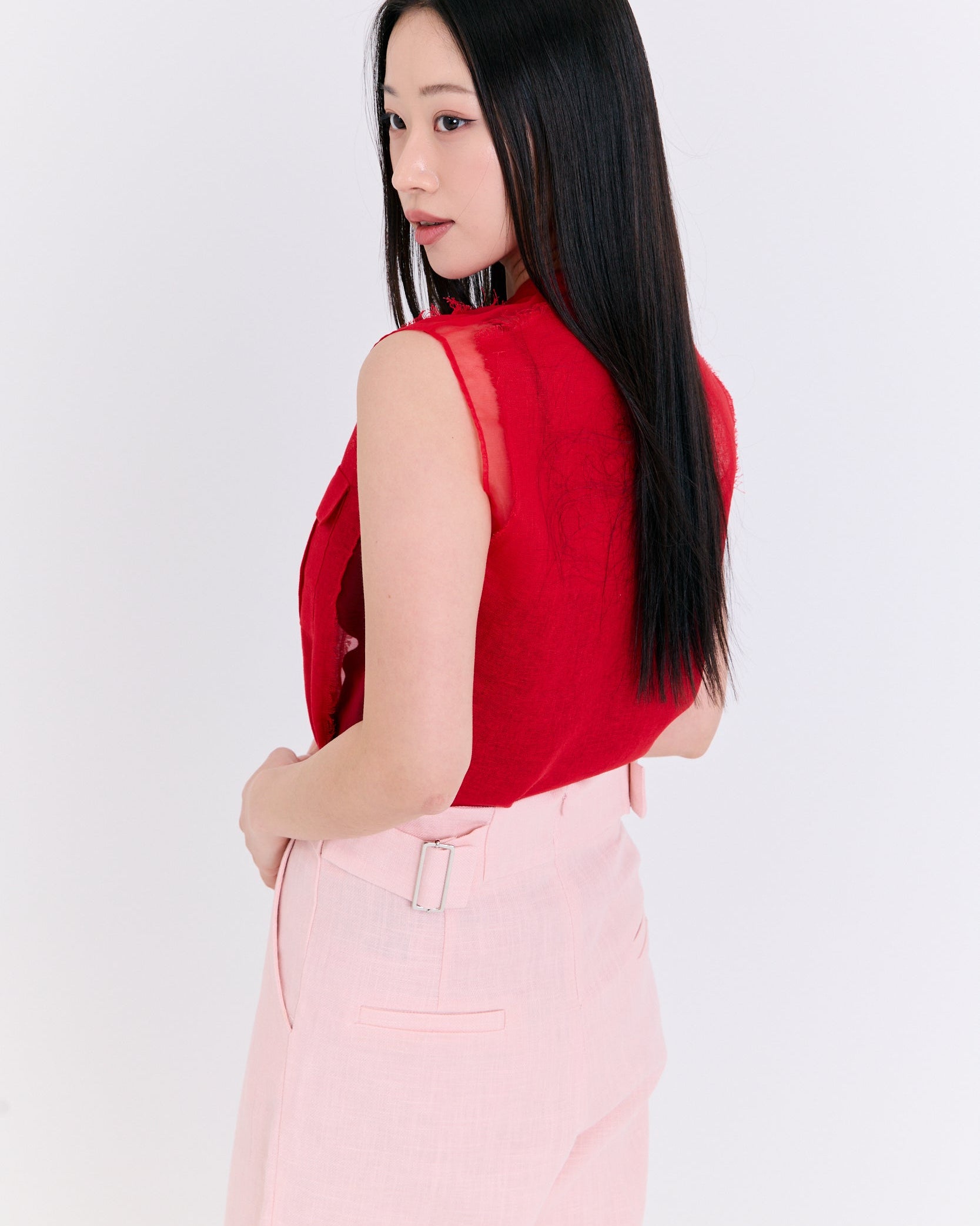 Woman wearing a red sleeveless top and pink pants on a white background