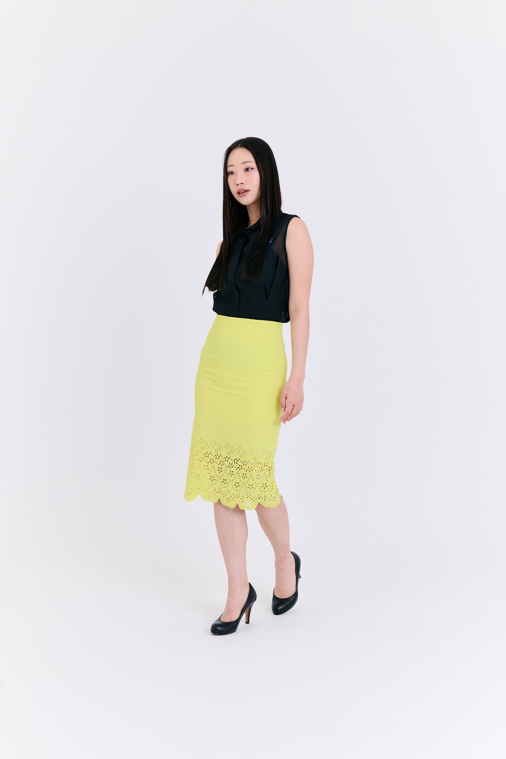 Woman wearing a black top and yellow skirt on a white background