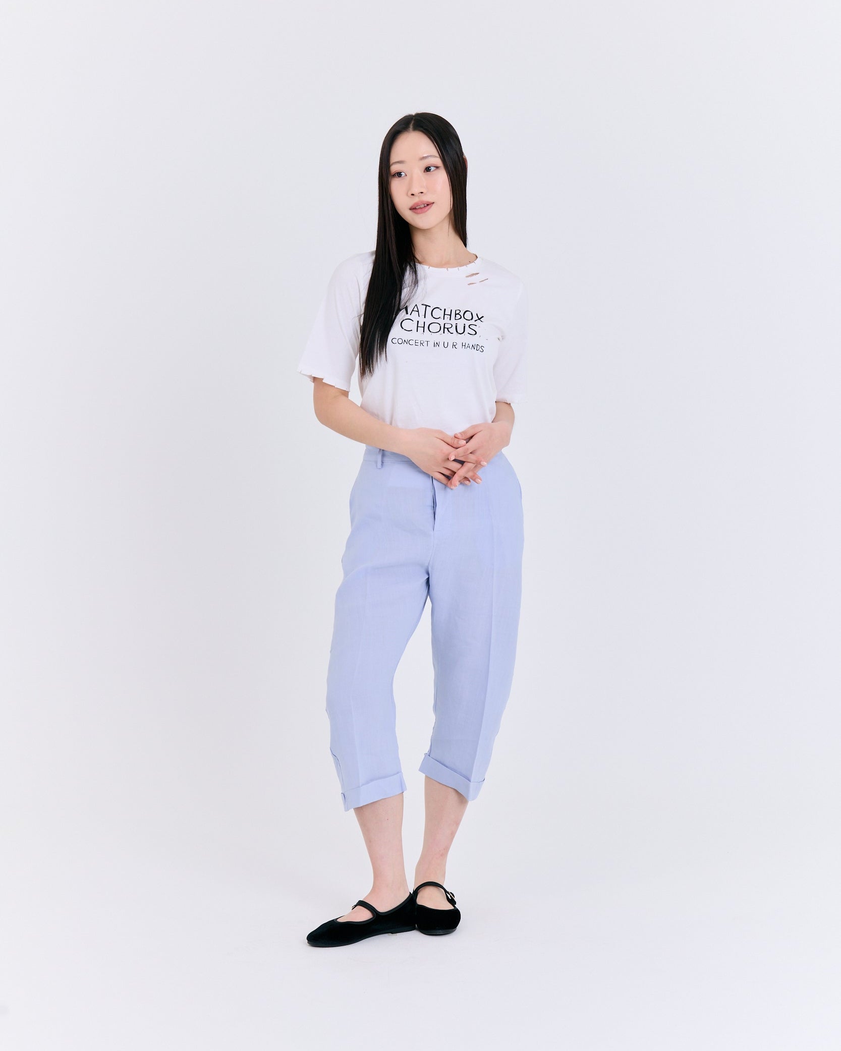 Person wearing a white t-shirt with text and light blue pants on a white background